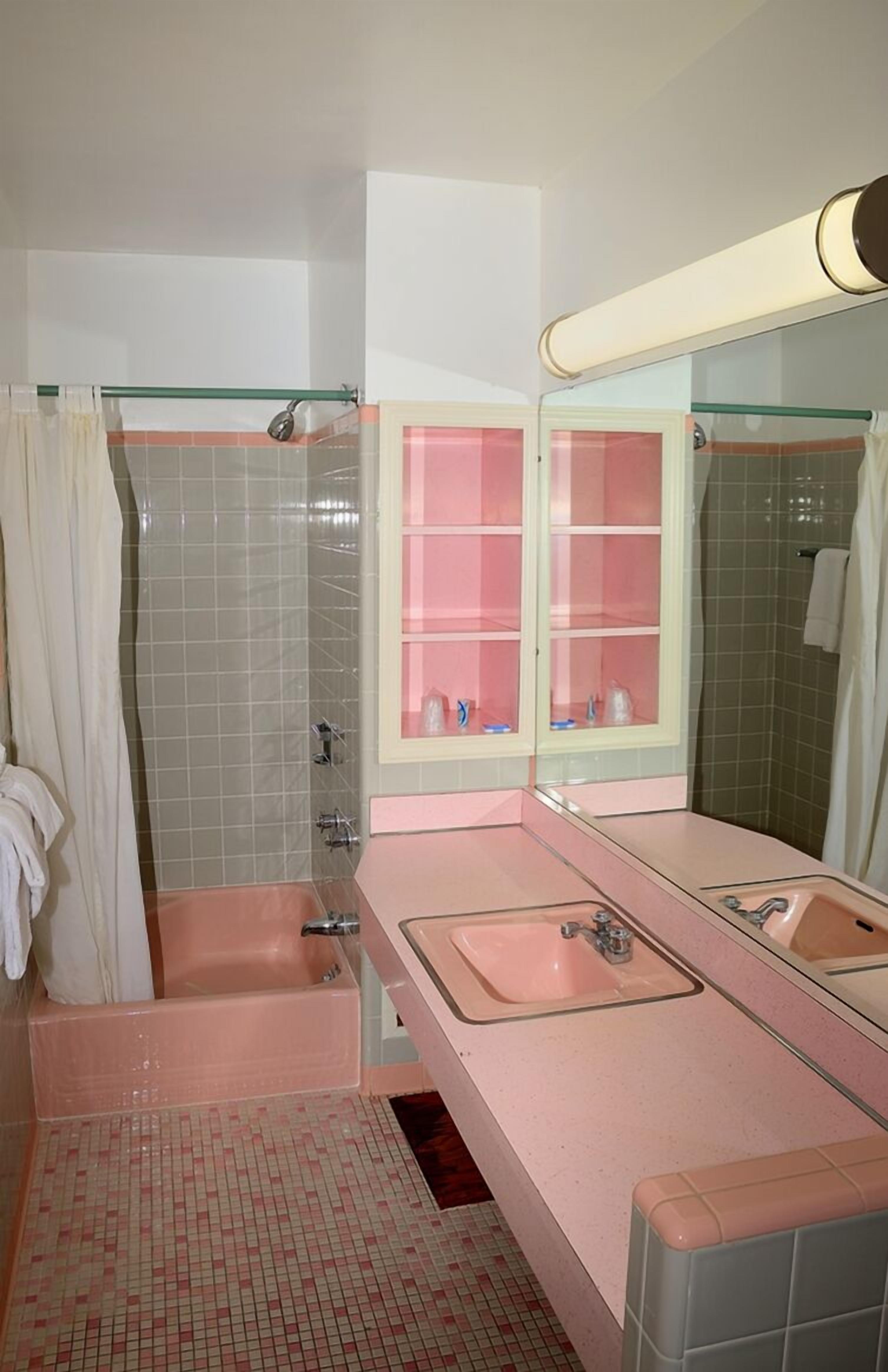 Une salle de bain avec une baignoire, deux lavabos, une douche à parois de verre et un miroir avec un meuble intégré.