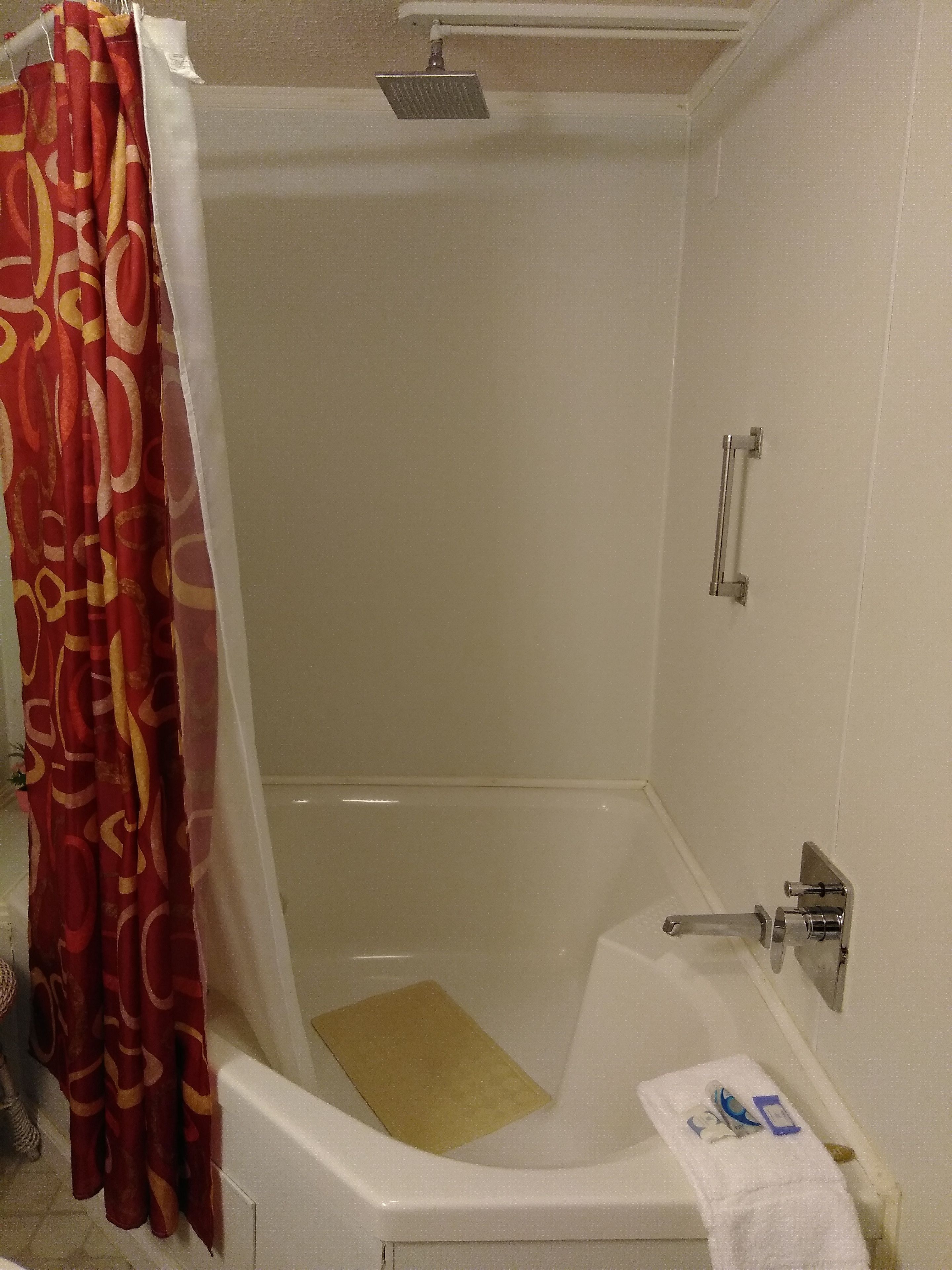 A bathroom with a bathtub, a showerhead, a towel rack, and a curtain.