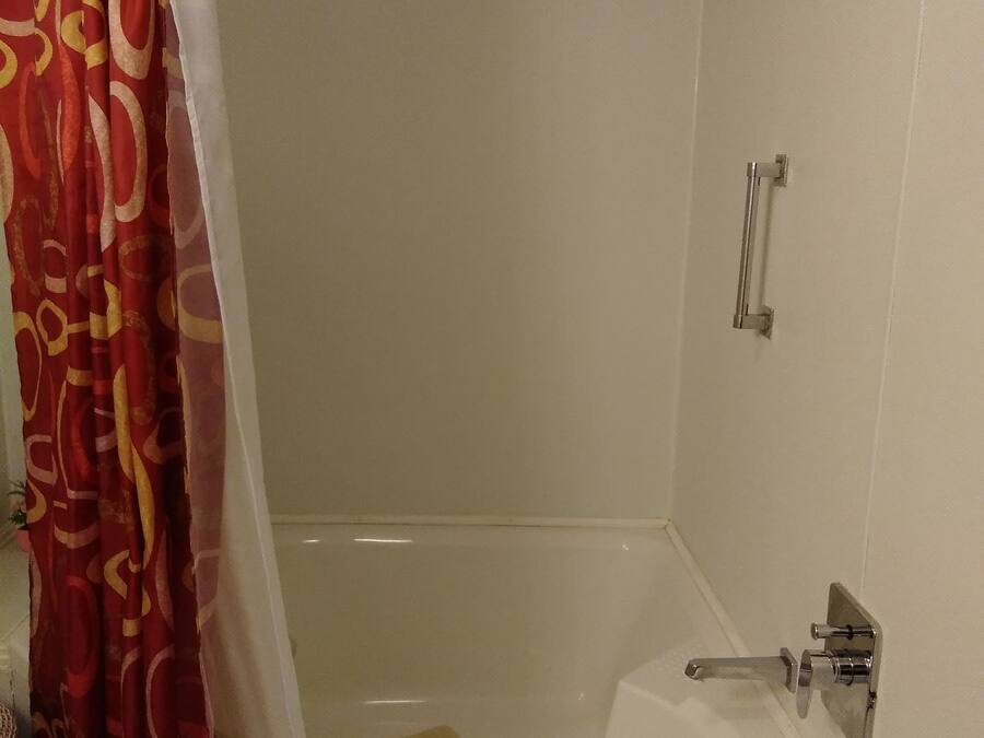 A bathroom with a bathtub, a showerhead, a towel rack, and a curtain.