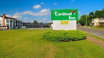A sign for Cardinal Inn with a green background and white lettering.