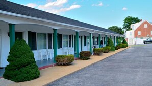 Una hilera de habitaciones de motel con ventanas de marco verde y paredes blancas.