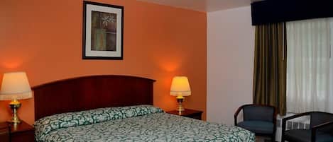 A hotel room with a bed, two bedside lamps, a chair, a window with curtains, and a framed picture on the wall.