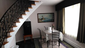 Un comedor con una mesa, sillas, un cuadro y una escalera.