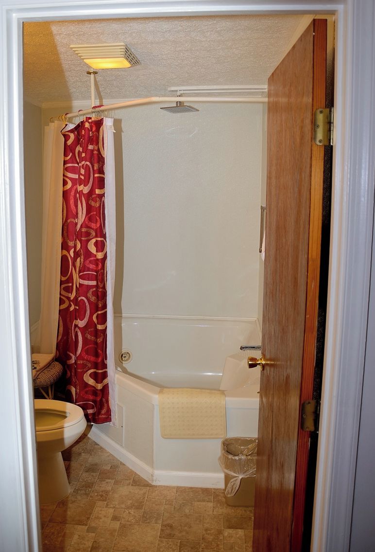 A bathroom with a bathtub, toilet, and shower curtain.
