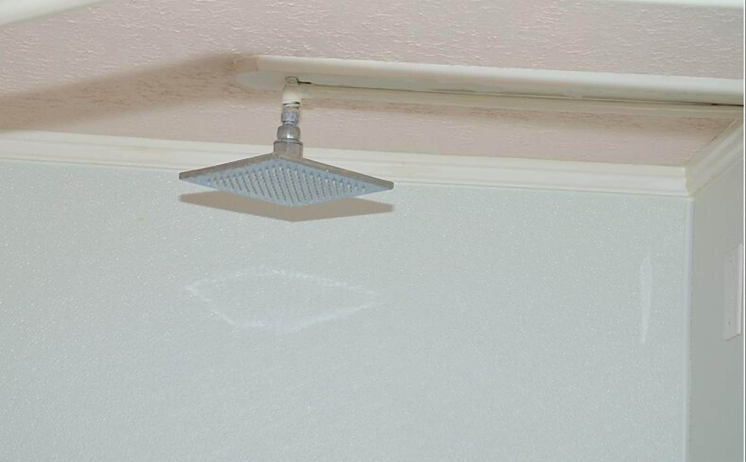 Esquina de un cuarto con techo blanco y ducha.