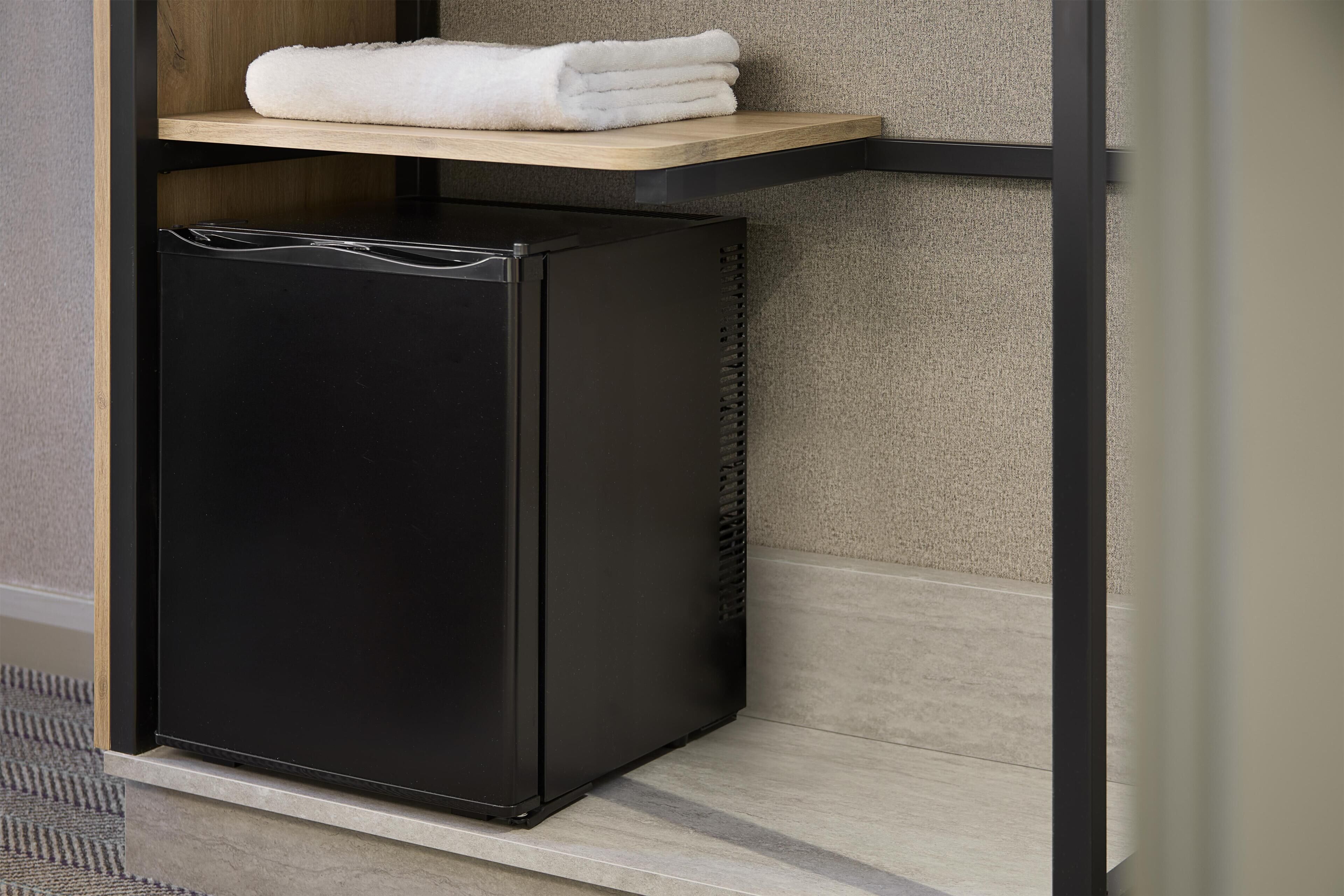 A black refrigerator with a wooden shelf above it.
