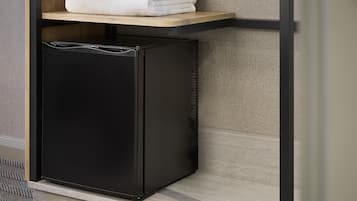 A black refrigerator with a wooden shelf above it.