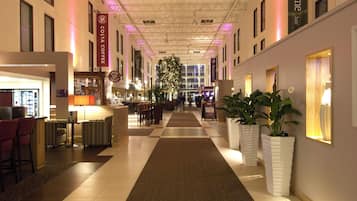 A hotel lobby with a reception desk, seating area, and a large plant.