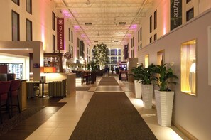 Un hall d’hôtel comprenant un comptoir d’accueil, un espace salon et une grande plante.
