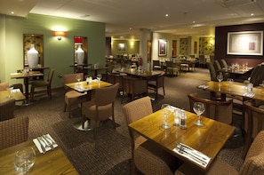 A hotel dining area with multiple tables and chairs, some with wine glasses and cutlery. - Premier Inn London Heathrow Airport T2 & T3 - Bath Road (Hounslow)