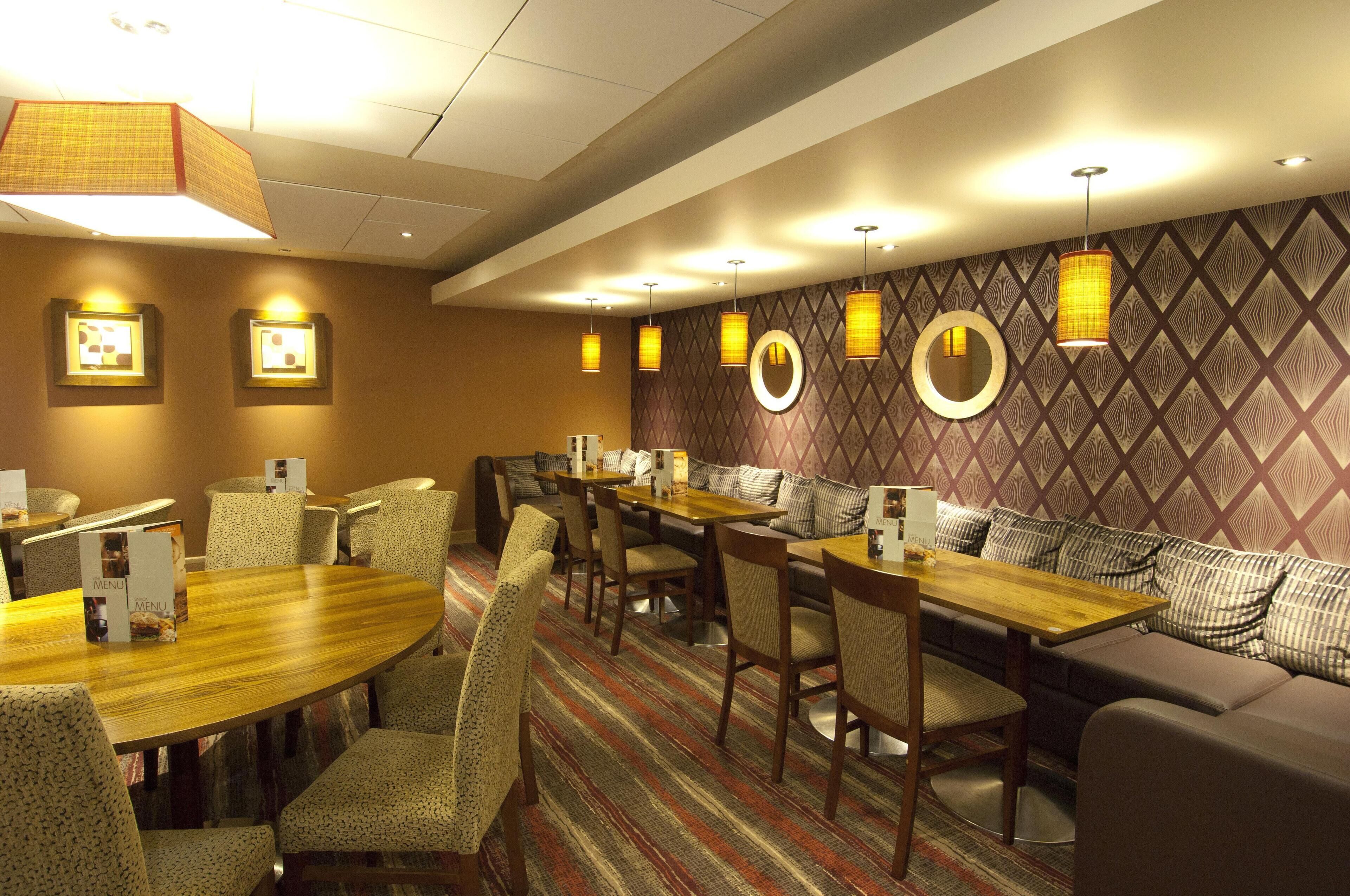 A hotel room with a dining area, a sofa, and a patterned wall.