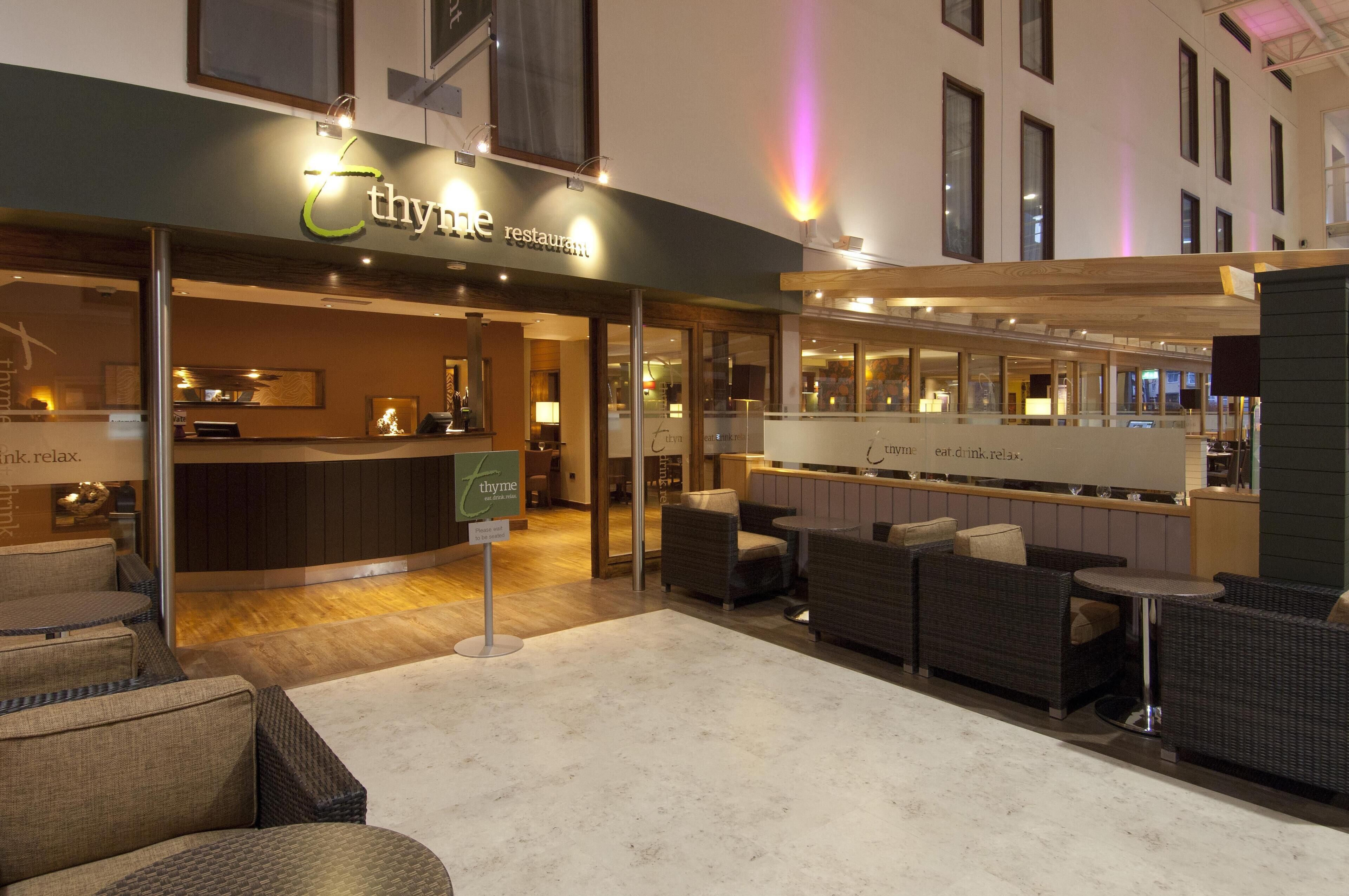 Un restaurante llamado 'thyme' con una zona de bar, asientos y un letrero que dice 'eat of ink relax'.