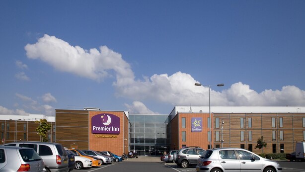 Ett Premier Inn-hotell med en parkeringsplats, en stor entré av glas och en fasad av tegel.