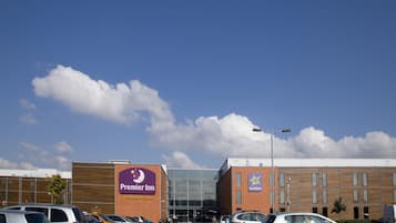 A Premier Inn hotel with a parking lot, a large glass entrance, and a brick building facade.