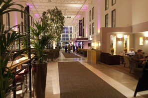 A hotel lobby with a reception desk, seating areas, and a large plant. - Premier Inn London Heathrow Airport T2 & T3 - Bath Road (Hounslow)