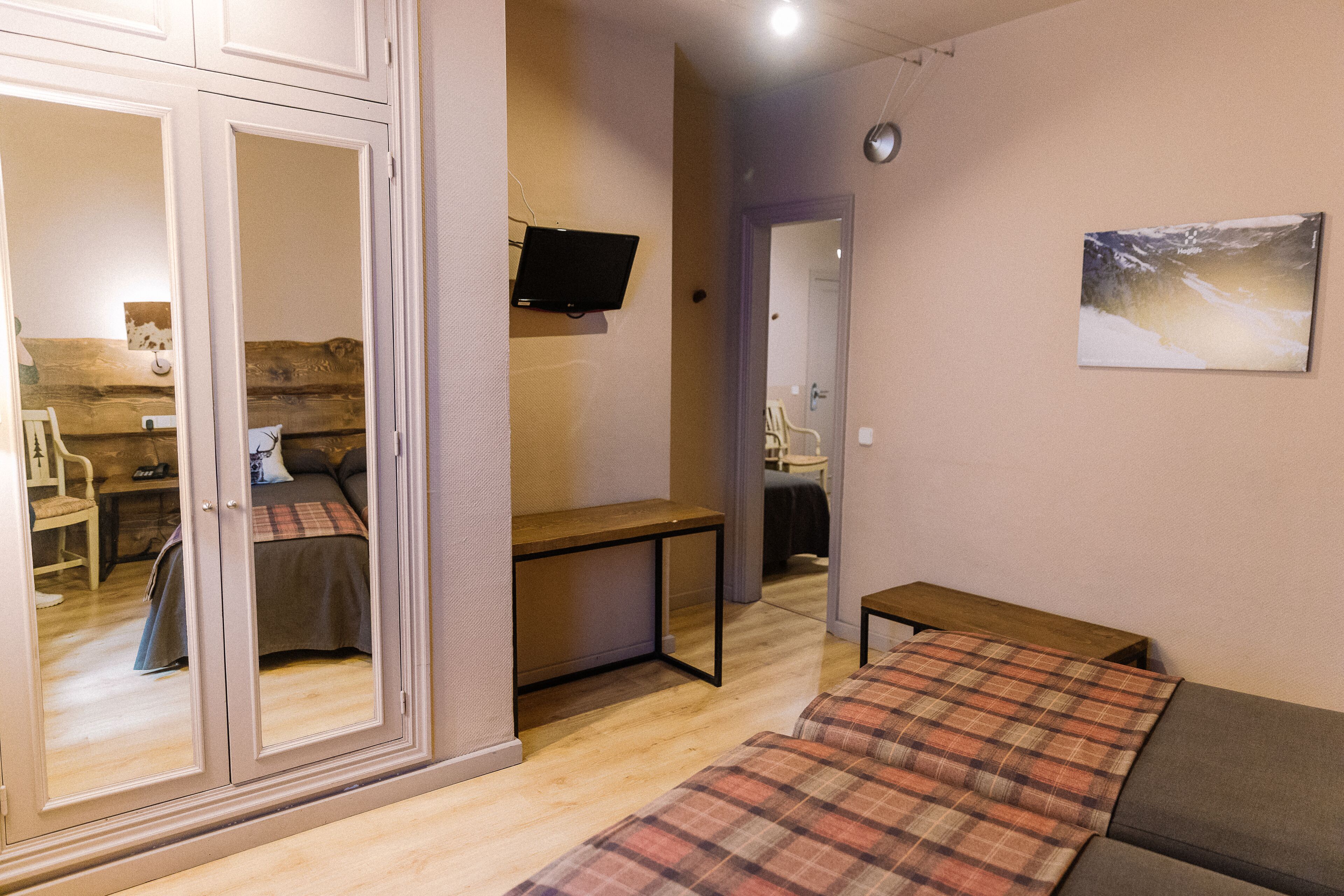 A room with a bed, a desk, a chair, a television, and a painting on the wall.
