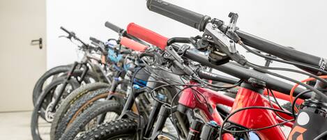 A row of bicycles parked indoors, with a white door in the background.