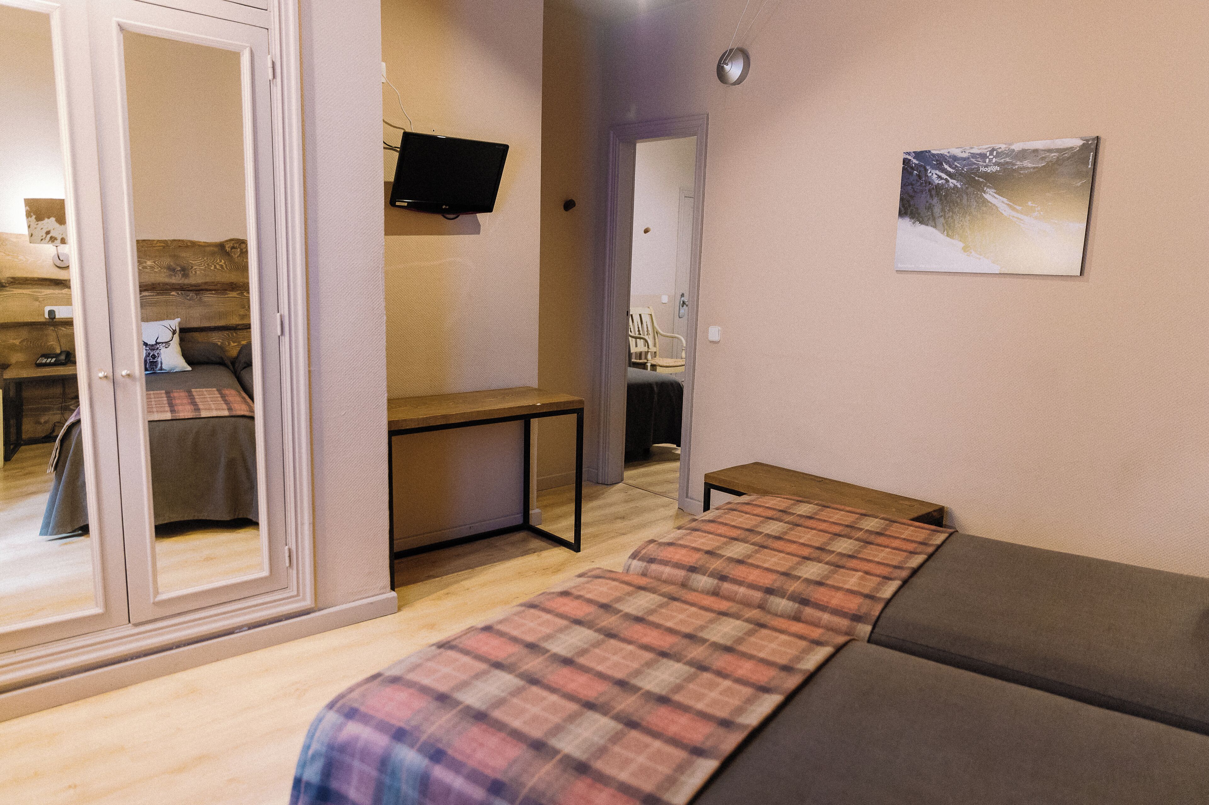 Una habitación con una cama, un escritorio, una silla y una televisión en la pared.