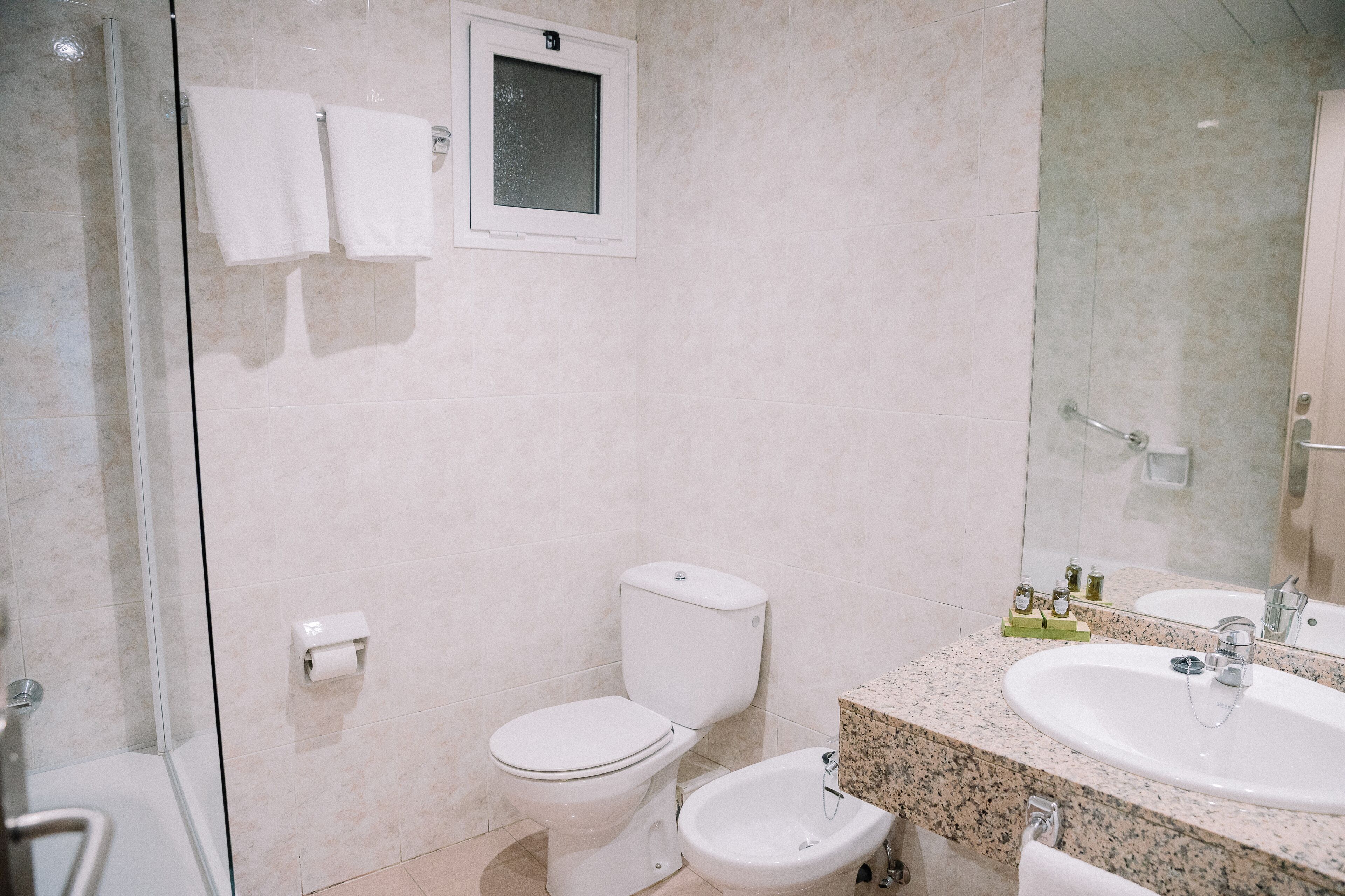 A bathroom with a toilet, bidet, and a sink with a mirror.