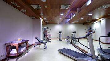 Un gimnasio con cintas de correr, elípticas y una banca.