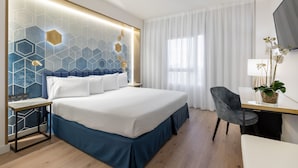 Habitació d'hotel moderna amb un llit gran, un escriptori i una cadira.