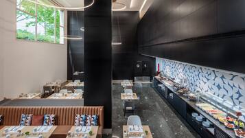 Ein modernes Restaurant mit einem Buffet, Sitzgelegenheiten und Blick auf Grünflächen.