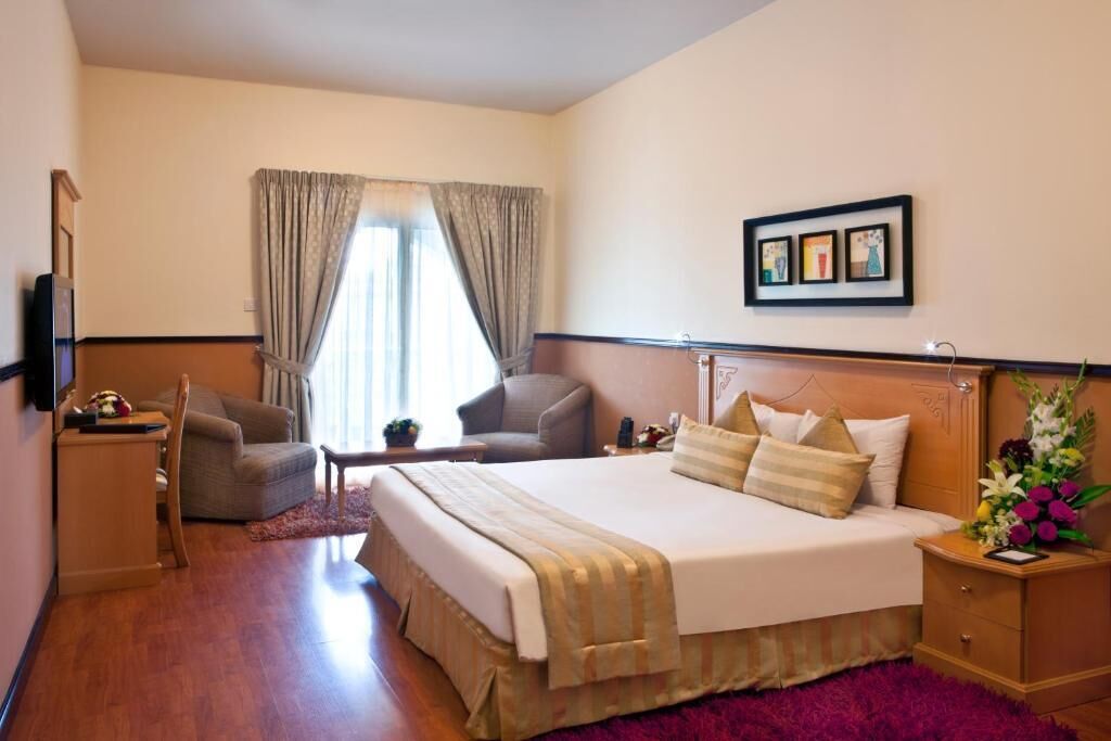 Una habitación de hotel con una cama grande, un escritorio, una silla y un televisor.