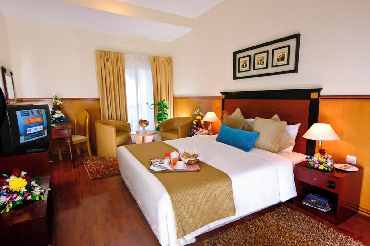 Une chambre d’hôtel avec un grand lit, deux tables de chevet, une télévision et un bureau avec une chaise.