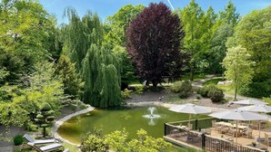 Un jardin avec un bassin, un espace aménagé pour s’asseoir et une terrasse dotée de parasols.