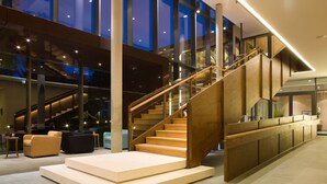 Un intérieur moderne avec un escalier, un coin salon et de grandes fenêtres.
