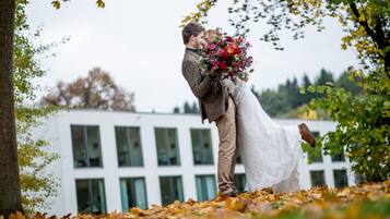 Una pareja abrazándose en un entorno natural, con un edificio al fondo.