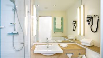 Un baño moderno con un lavamanos grande, una ducha y un espejo con toallero.