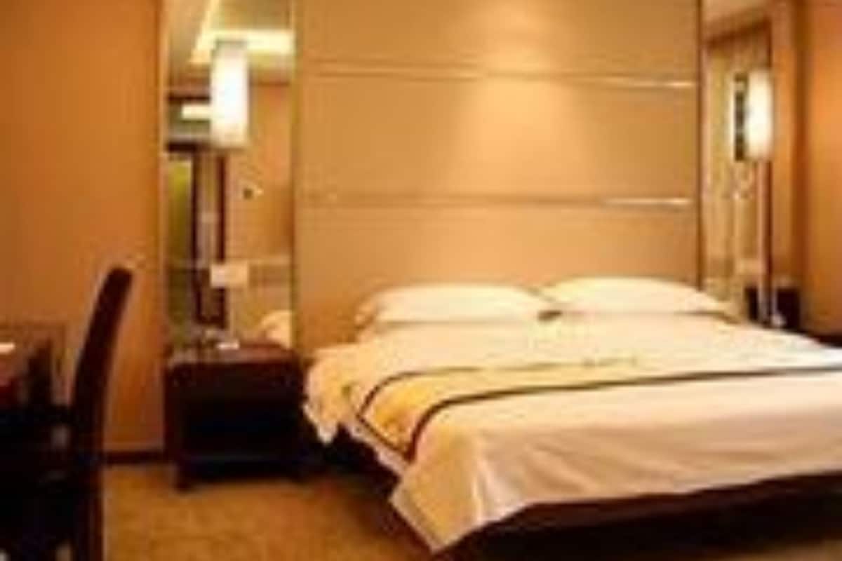 Une chambre d’hôtel avec un lit, une table de chevet, une lampe et un miroir.