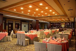 A banquet hall with round tables covered in pink tablecloths, arranged in rows.