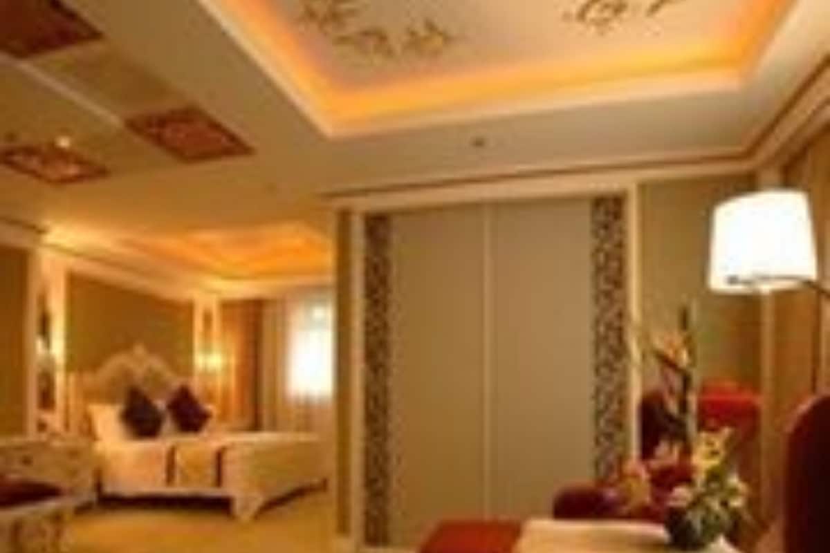 Une chambre d’hôtel avec un lit, un coin salon doté d’un canapé rouge et une lampe.
