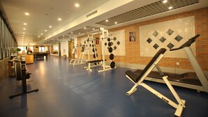 Uma academia com diversos equipamentos de ginástica, piso azul e parede de tijolos com padrão decorativo.