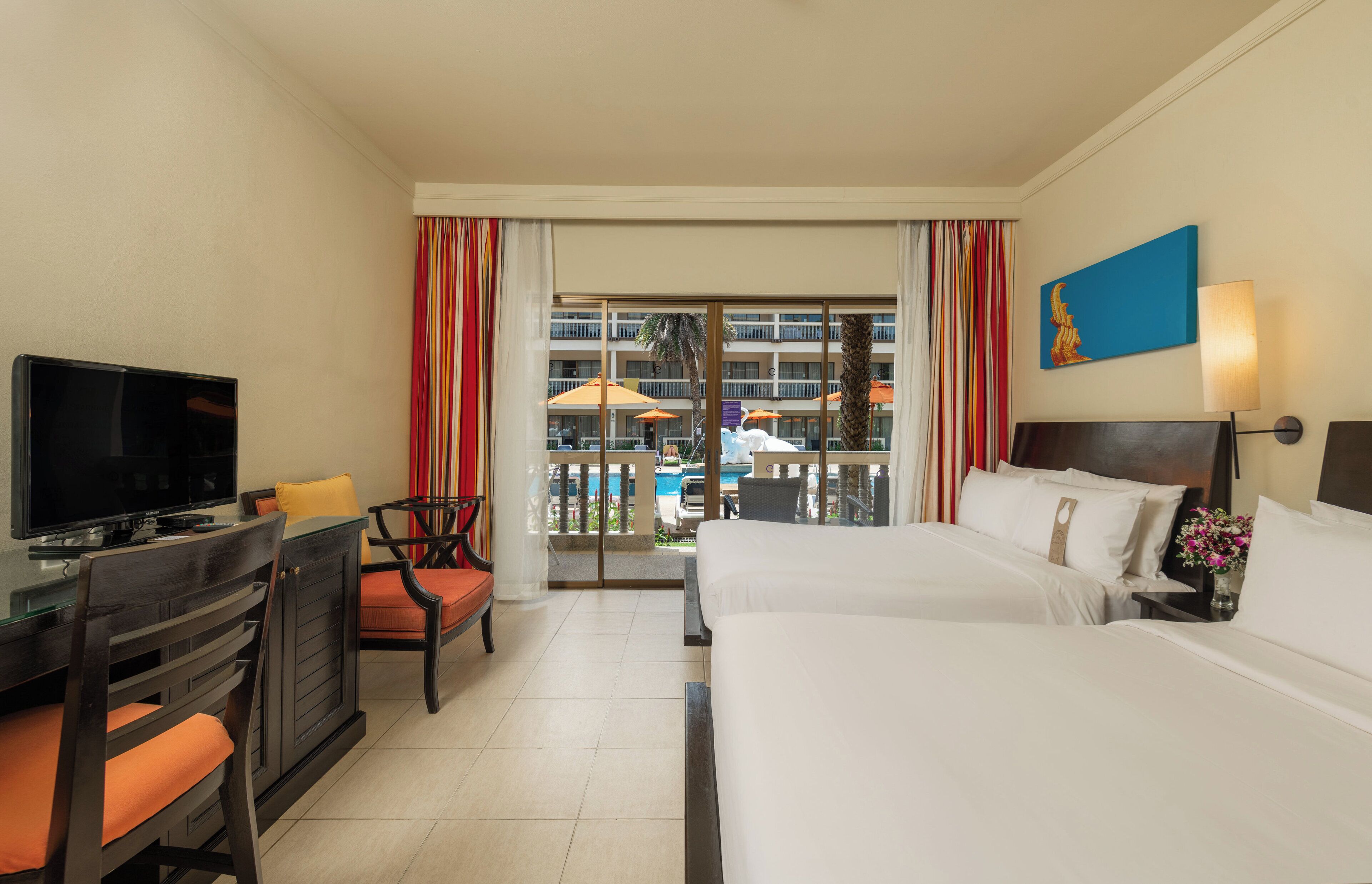 A hotel room with a TV, two beds, a desk, and a chair.