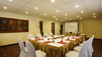 Un salón de conferencias con una larga mesa, sillas blancas y una pantalla de proyector que muestra "CENTARA".