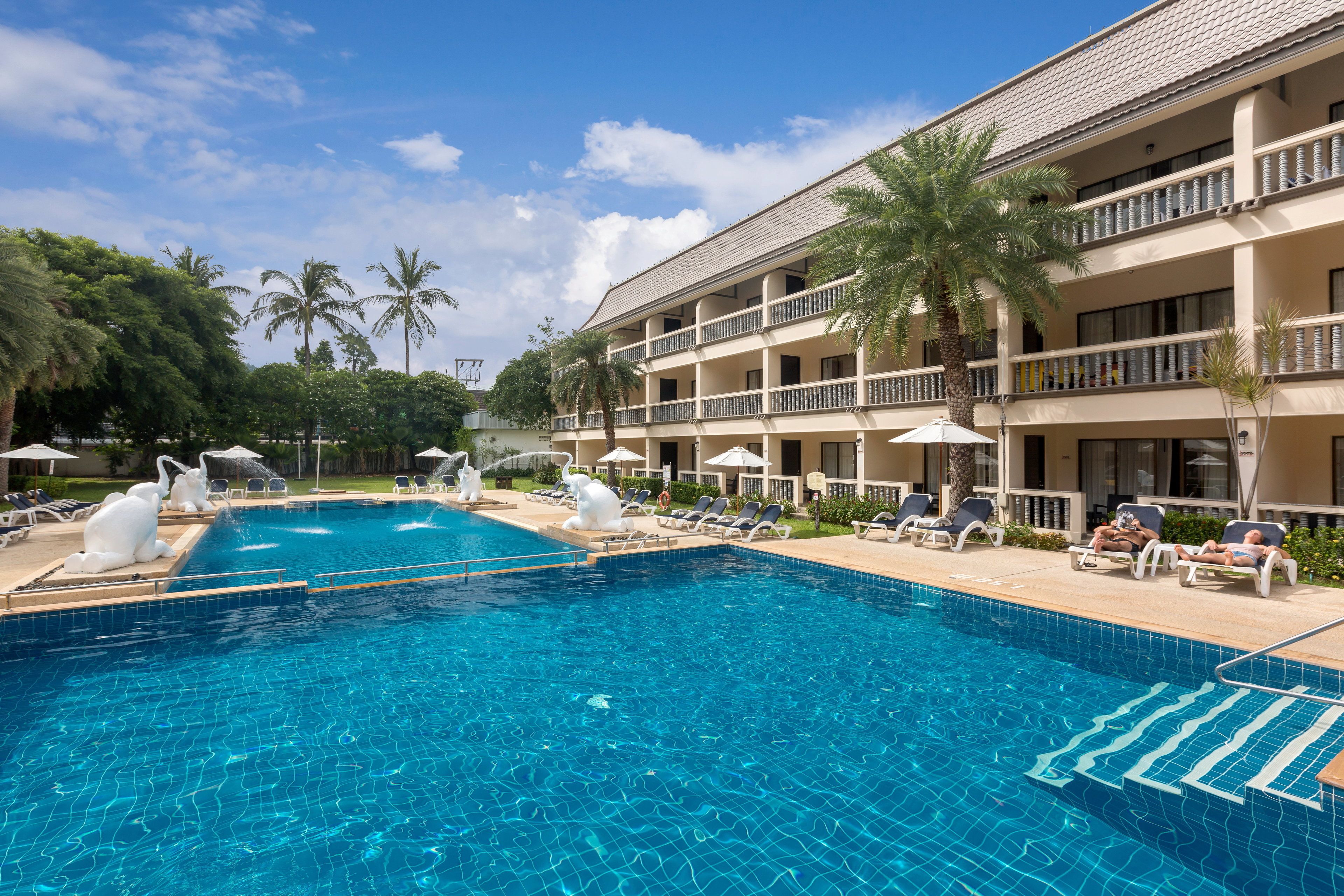 A swimming pool with lounge chairs and palm trees.