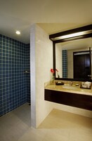 Un baño con pared de azulejos azules, un lavamanos blanco y una encimera oscura.