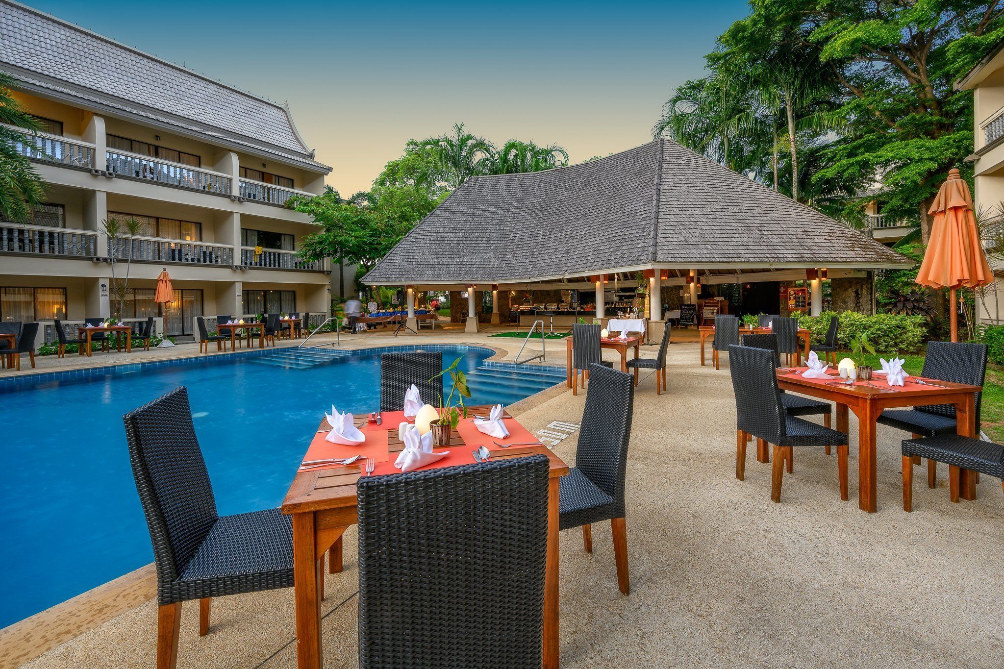 A hotel pool area with outdoor seating and a covered dining area.
