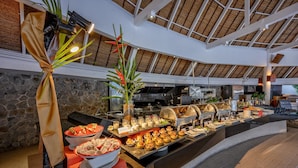 A buffet area with various food options, a stone wall, and a high ceiling with wooden beams.