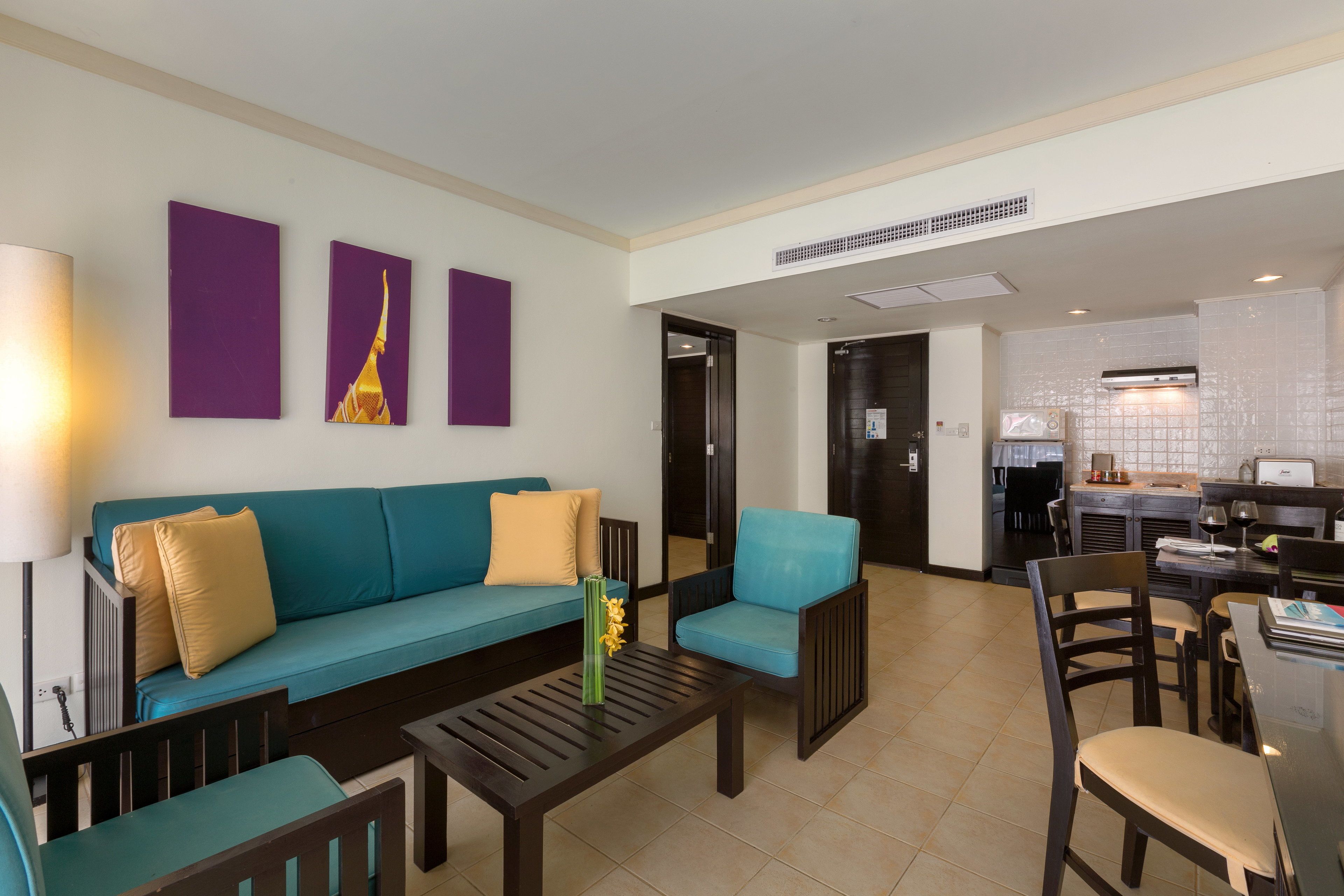 A modern living room with a teal sofa, a coffee table, and a dining area with a table and chairs.