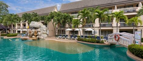 Un hotel con piscina, palmeras y una formación rocosa.
