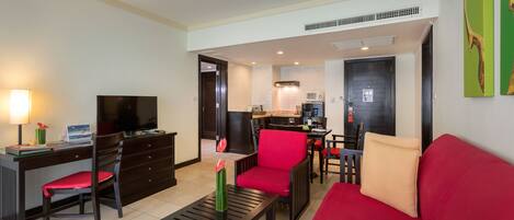 A modern living room with a red sofa, a coffee table, a TV, and a dining area with chairs and a table.