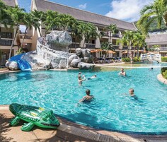 A pool area at Kata Resort Phuket with a slide, palm trees, and a rocky feature.