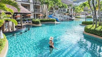 A swimming pool at Centara Kata Resort Phuket with clear water, palm trees, and a person swimming.