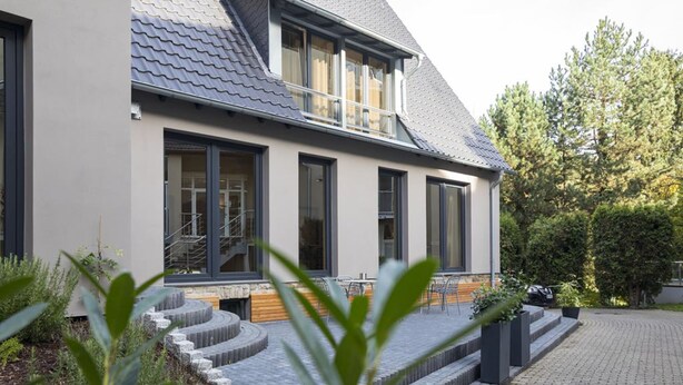 A modern two-story house with a grey tiled roof, large windows, and a staircase leading to the entrance. - Wald & Golfhotel Lottental (Bochum)