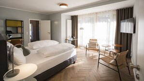 A hotel room with a bed, bedside tables, a desk, a chair, a TV, and a window with curtains. - Wald & Golfhotel Lottental (Bochum)