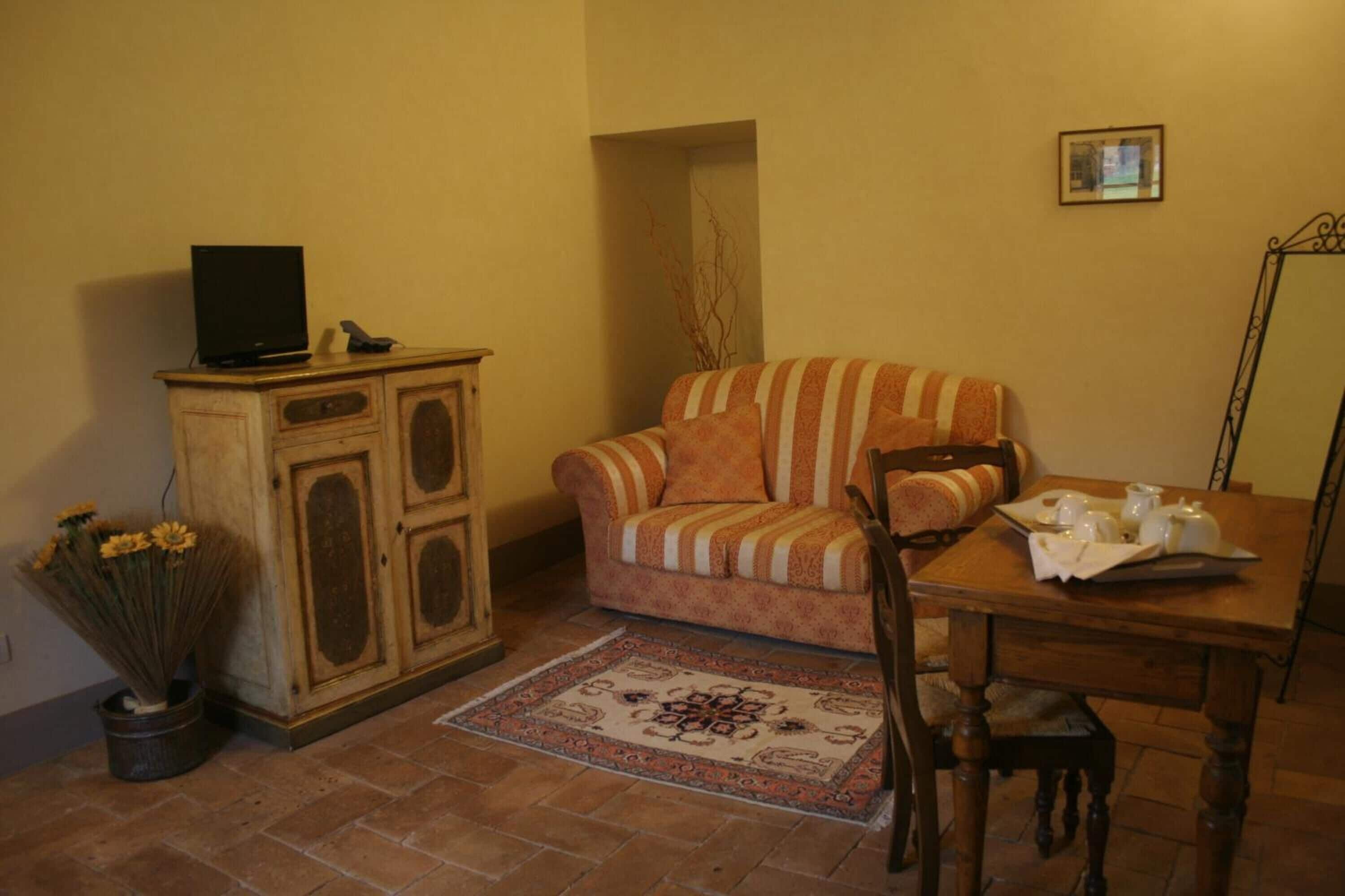 Un accogliente soggiorno con un divano, un mobiletto in legno con televisore, un tavolo da pranzo con sedie e un tappeto decorativo.